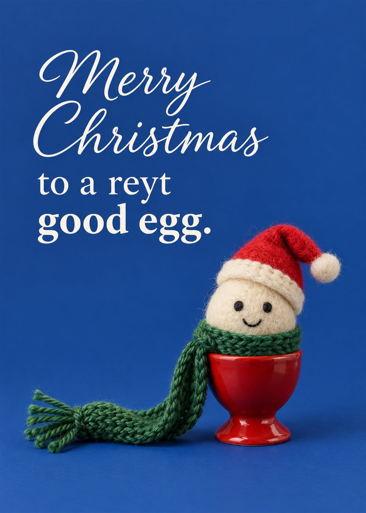 Funny Christmas card showing a needle-felted egg with a smiley face wearing a Santa hat and green scarf in a red, by Gigglz
